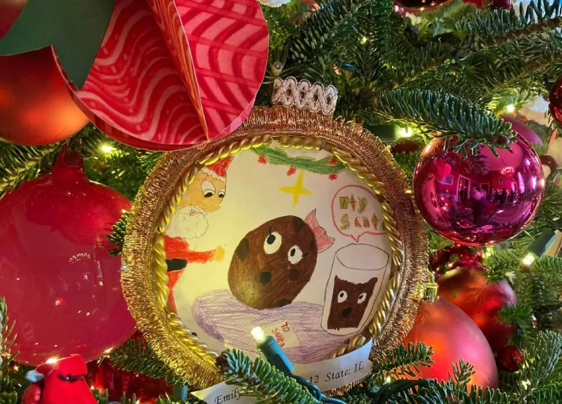 Xiritaanka qurxinta geedka kirismaska ​​ee uu ka muuqdo sawirka ilmaha oo lagu xardhay dahab. Sawirka midabka leh ayaa muujinaya buskud noole ah iyo caano.