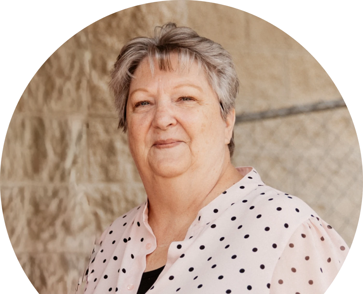 Haweeney da' ah oo timo gaaban oo cirro leh ayaa si tartiib ah u dhoola cadeynaysa iyada oo xidhatay blouse-ka dhibicda cad cad. Dhabar-dugsiyeedku wuxuu muujinayaa gidaar muuqaalaysan, beige oo leh xayndaab silsilad-xiran.